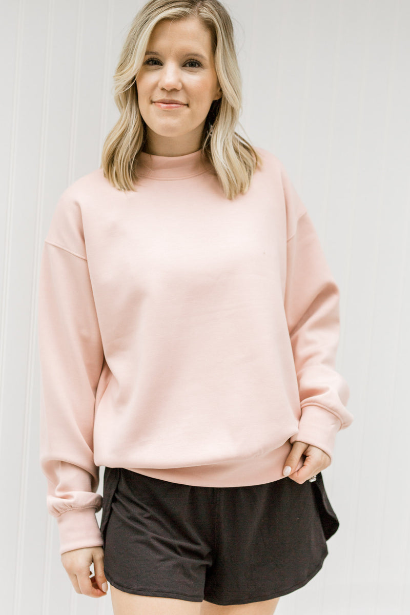 Blonde model wearing a pink sweatshirt with black shorts.