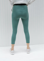 Back view of model wearing teal capri yoga pants.