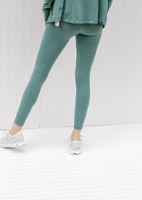 Back view of model wearing teal leggings.