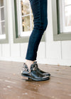 Side view of Black bootie with low stacked heel, decorative straps and o-ring accents