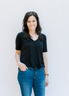 Model wearing a black, v-neck, short sleeve top with a chest pocket made of bamboo material. 