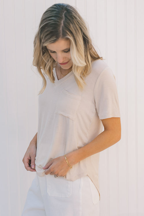 Model wearing a cream, short sleeve tee with a front pouch pocket 