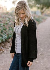 Blonde model wearing black cardigan with white top. 