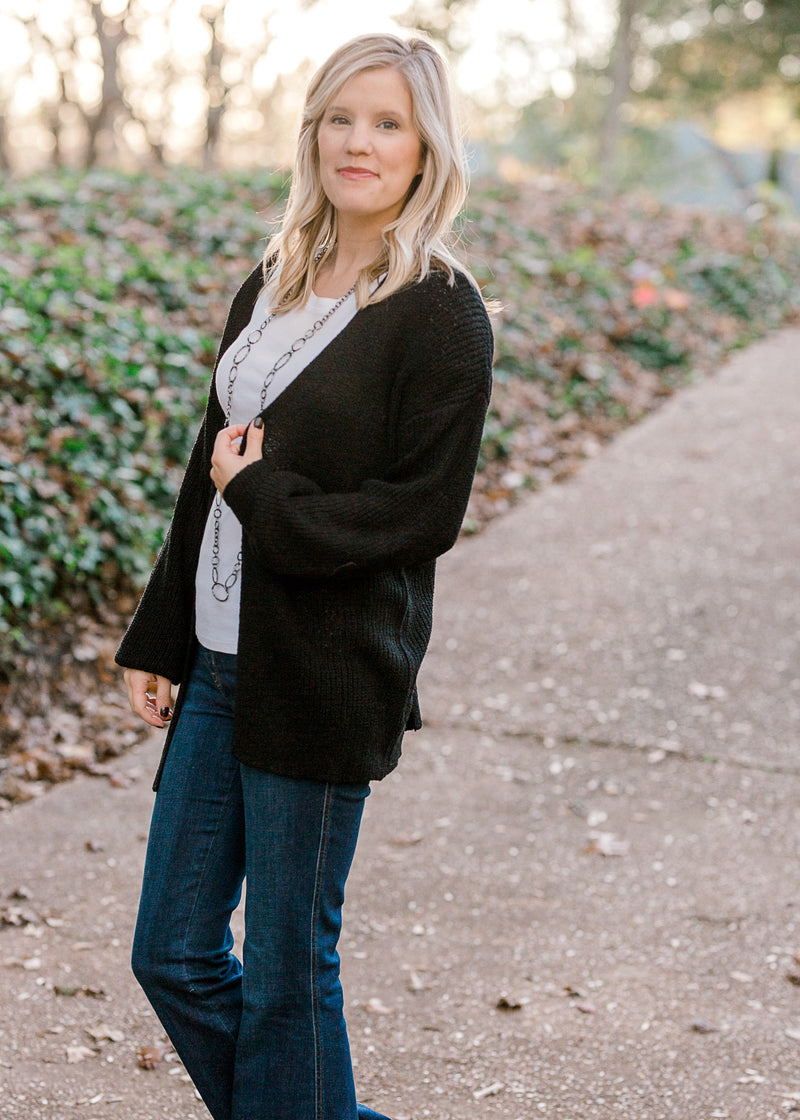 Blonde model wearing black cardigan with jeans. 