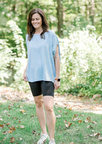 Smiling brunette model wearing black bike shorts and workout top.