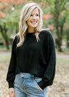Blonde model wearing a black sweater.