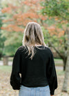Back view of Blonde model wearing a black sweater.