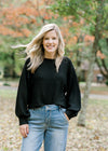 Blonde model wearing a black sweater with jeans.