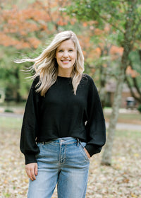 Blonde model wearing a black sweater with jeans.