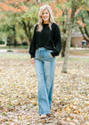 Blonde model wearing a black sweater with jeans and booties.