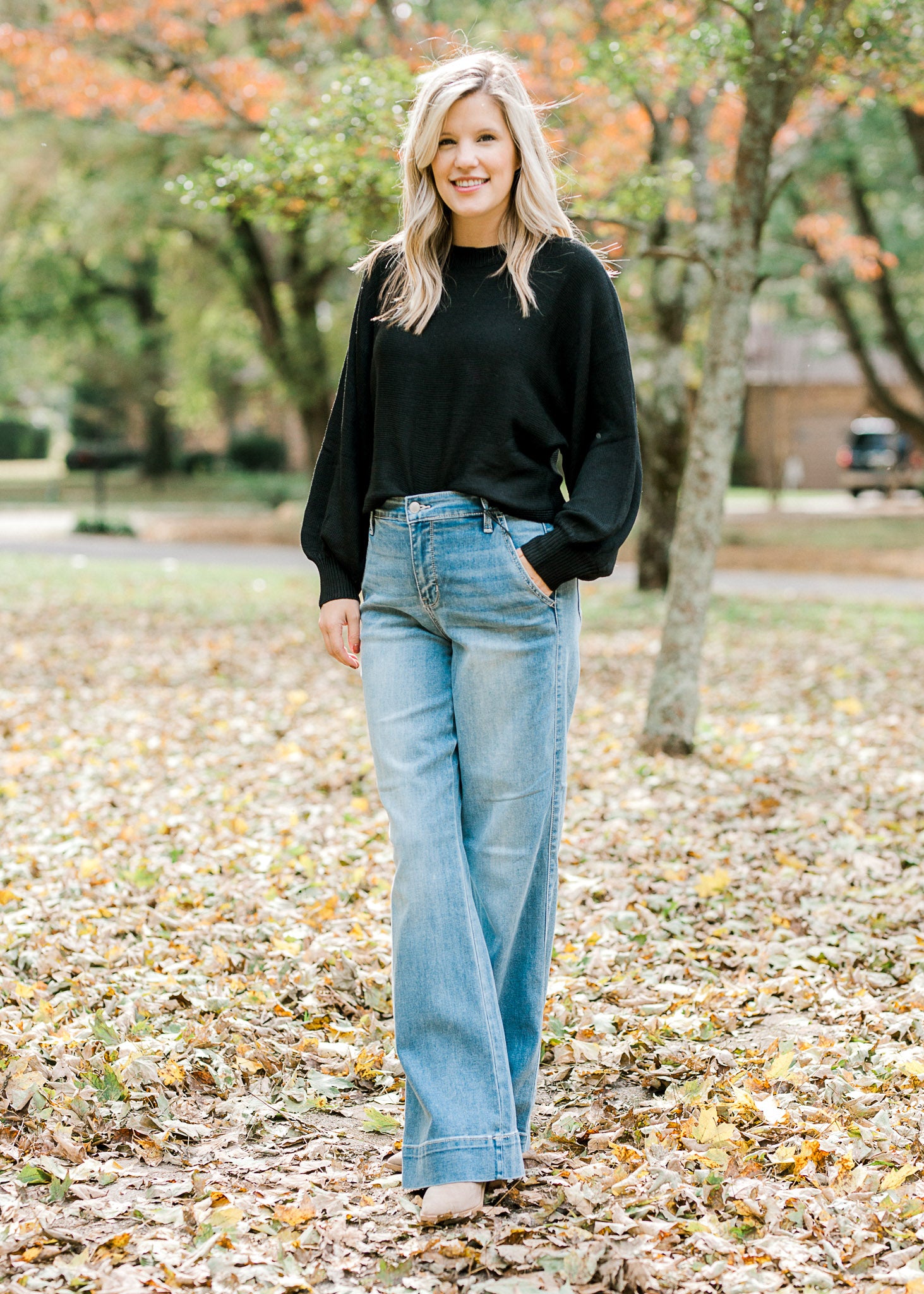 Blonde model wearing a black sweater with jeans and booties.