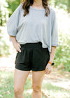 Brunette model wearing black elastic waist tulip shorts.