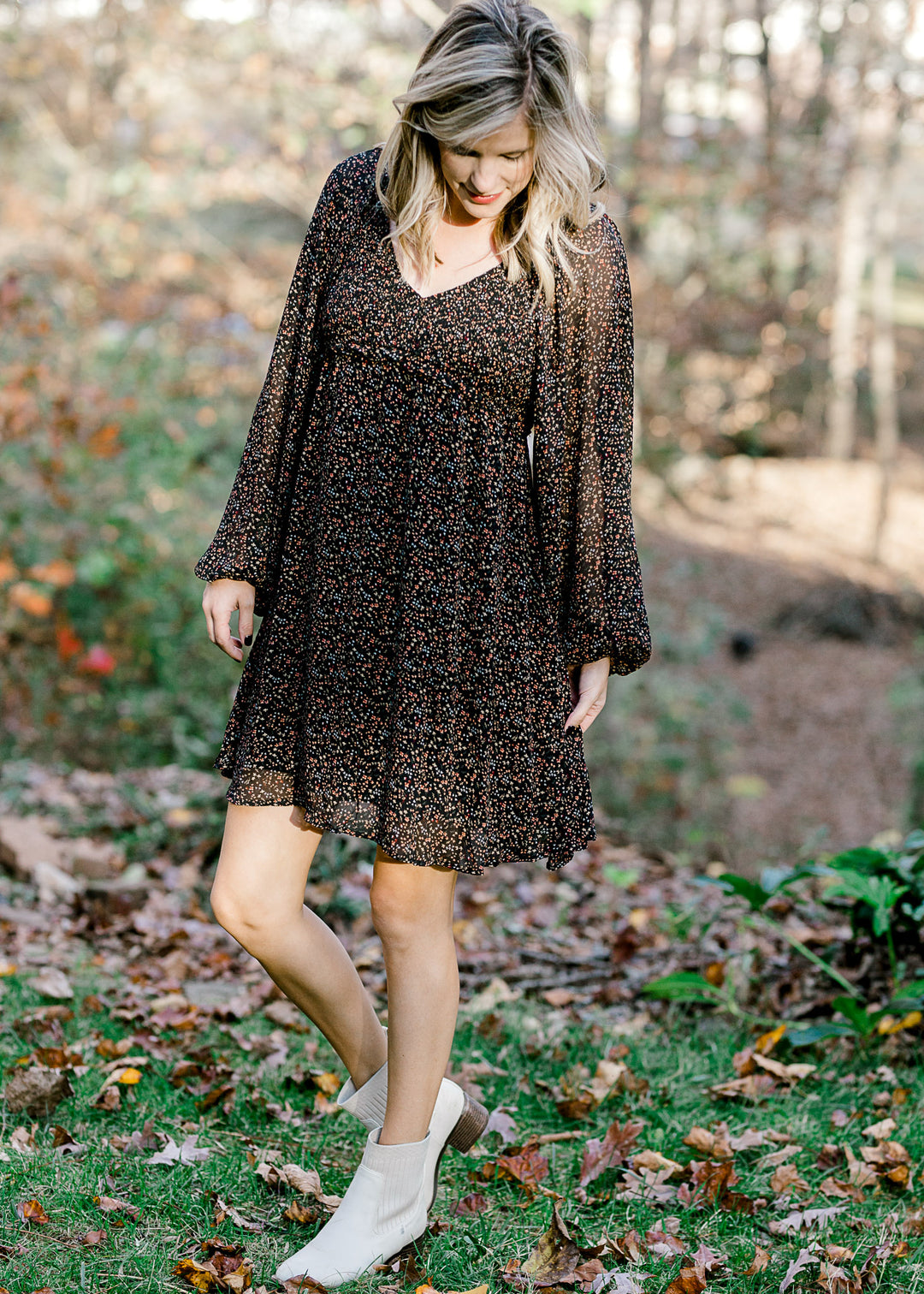 Blonde model wearing black dress with ditsy pink floral pattern and booties. 