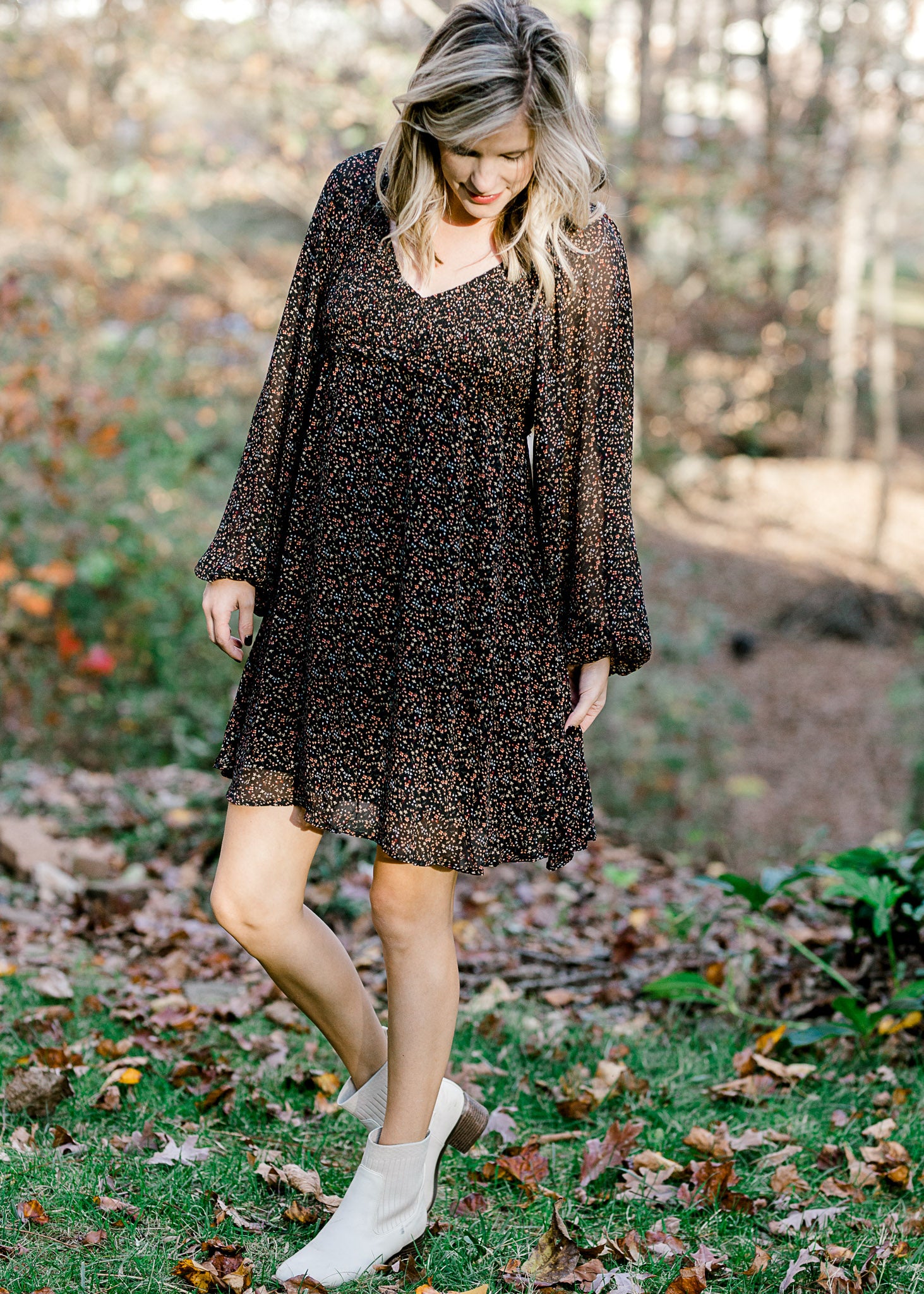Blonde model wearing black dress with ditsy pink floral pattern and booties. 