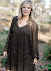 Blonde model wearing black, v-neck dress with ditsy pink floral pattern. 