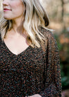 Close up view of Blonde model wearing black dress with ditsy pink floral pattern. 