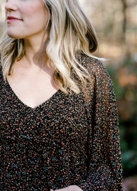 Close up view of Blonde model wearing black dress with ditsy pink floral pattern. 