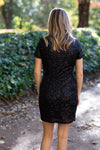Back view of Blonde model wearing black sequin dress.