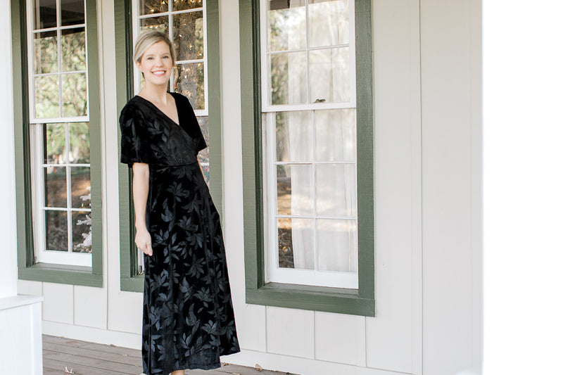 Blonde mode wearing floral tone on tone black velvet dress outdoors.
