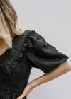 Close up view of eyelets and smocked bodice on black dress.