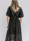 Back view of blonde model wearing a black dress. 