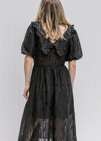 Back view of blonde model wearing a black dress. 