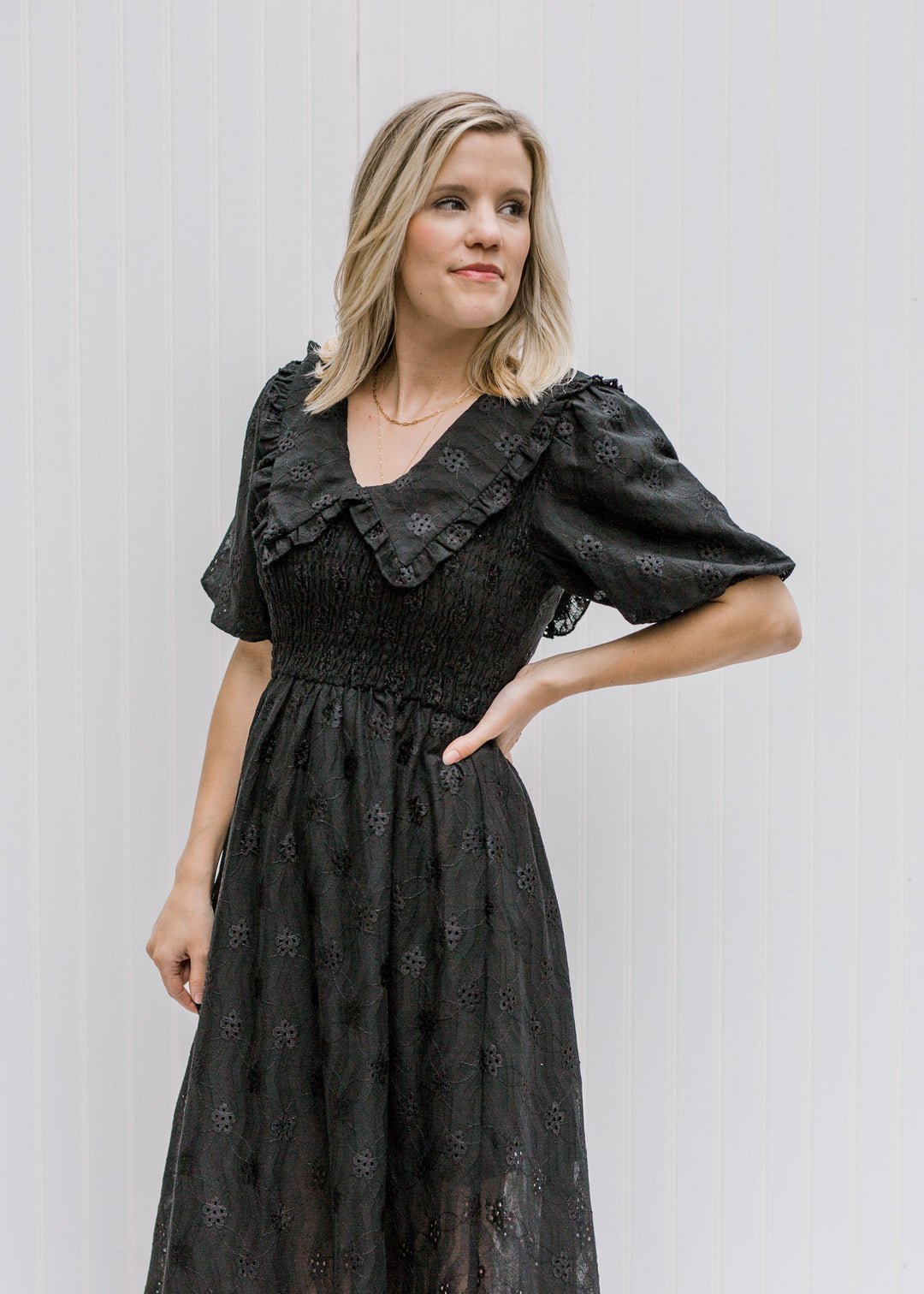 Blonde model wearing black dress with eyelets.
