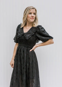 Blonde model wearing black dress with eyelets.