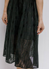 Model wearing a black dress with sheer overlay