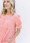 Close up view of bubble short sleeve on a tiered pink dress with a round neck.