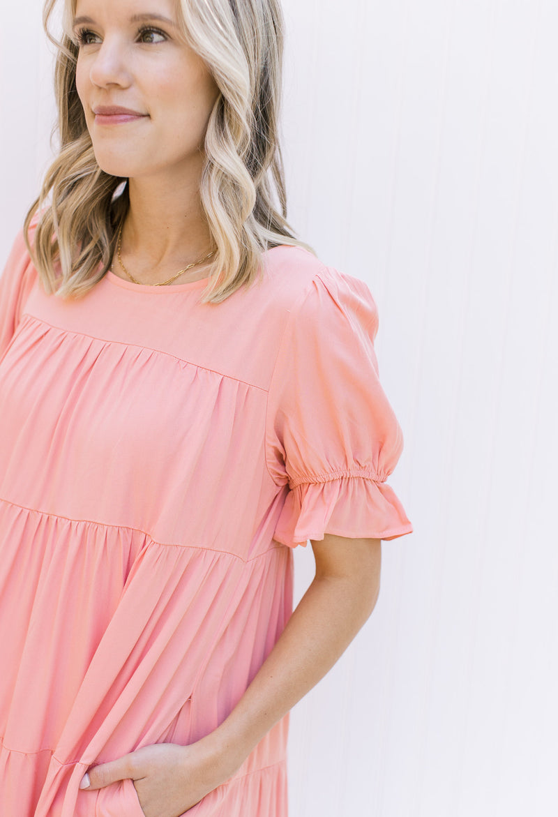 Close up view of bubble short sleeve on a tiered pink dress with a round neck.