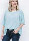 Blonde model wearing a light blue short sleeve top.