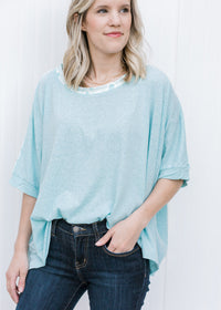 Blonde model wearing a light blue short sleeve top.