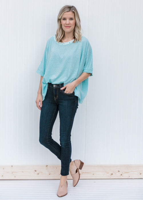 Blonde model wearing a light blue top with jeans and heels.