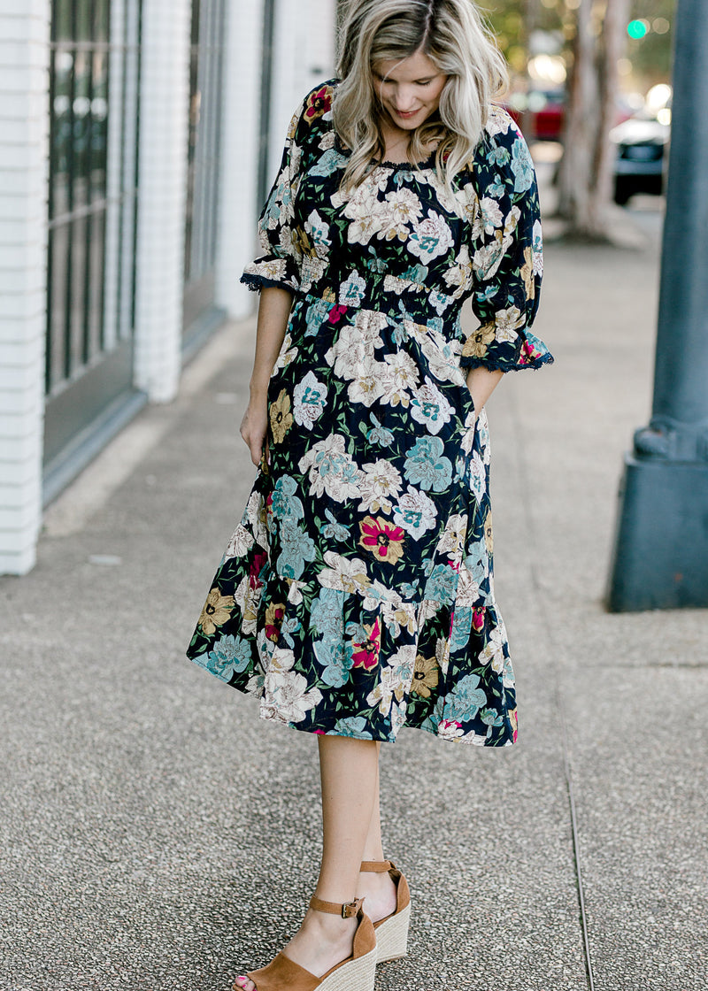 Blonde model wearing navy midi dress with floral pattern  and wedges.