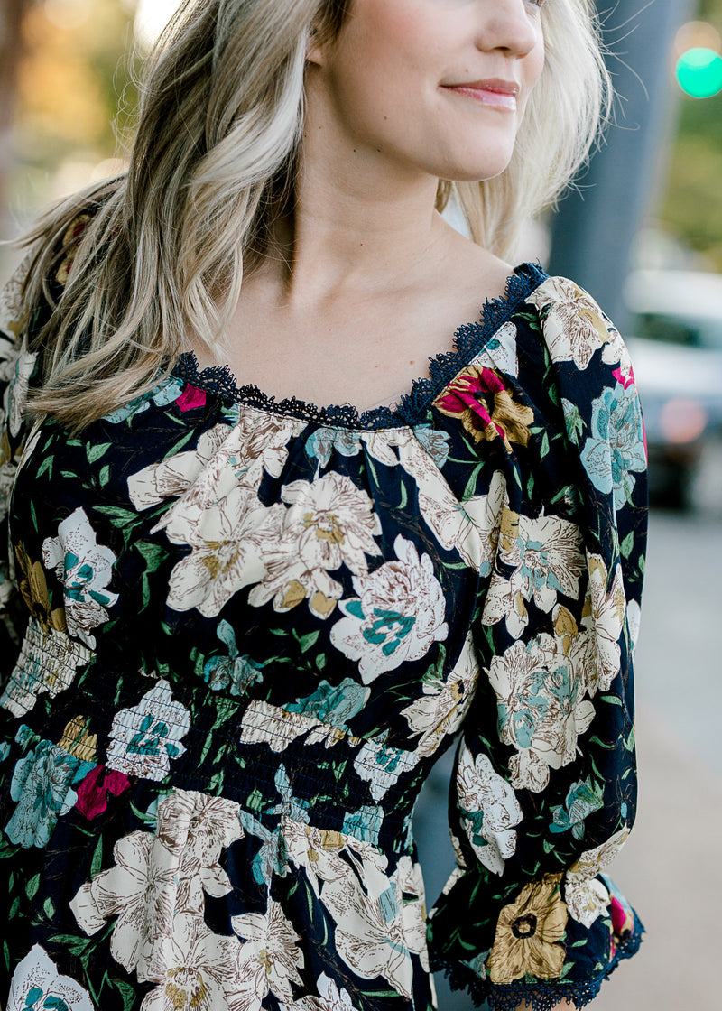 Close up view of Blonde model wearing navy midi dress with floral pattern.