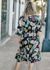 Back view of Blonde model wearing navy midi dress with floral pattern.