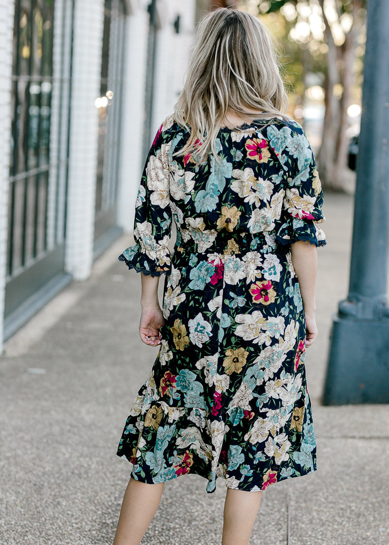 Back view of Blonde model wearing navy midi dress with floral pattern.