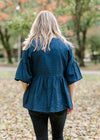 Back view of Blonde model wearing navy checked button up top.