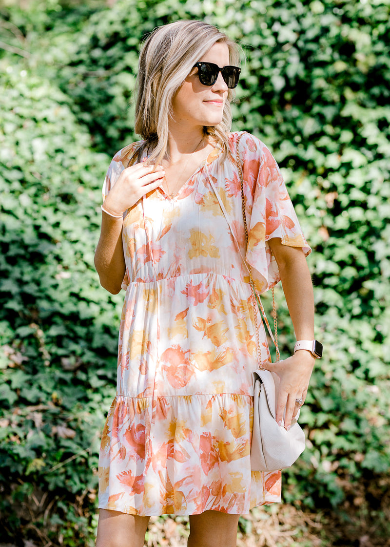 Blonde model wearing floral dress and black sunglasses with gold accents.