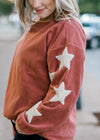 Close up of star detail on the sleeve of a mauve sweater. 
