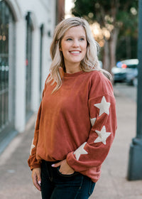 Blonde model wearing mauve colored top with cream star detail on arm.