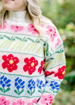 Close up view of bright floral pattern on cream sweater. 