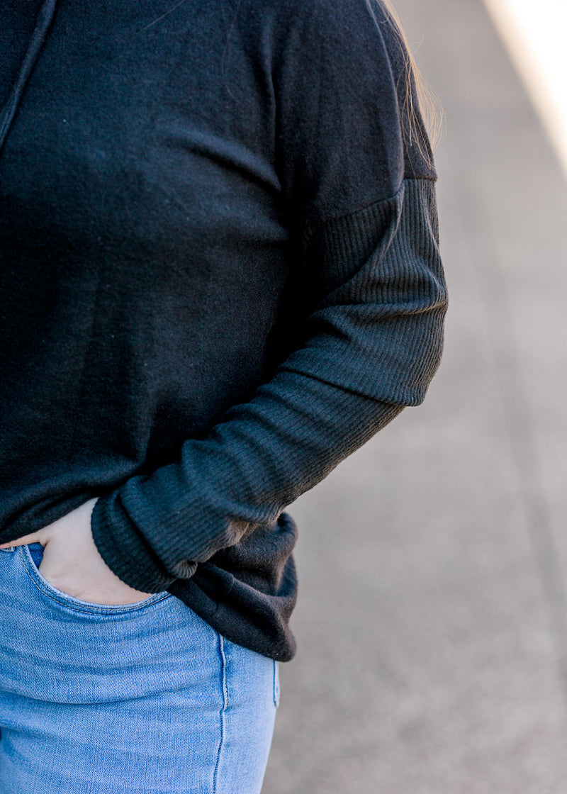 Close up view of Brunette model wearing black hoodie.