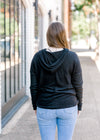 Back view of Brunette model wearing black hoodie.