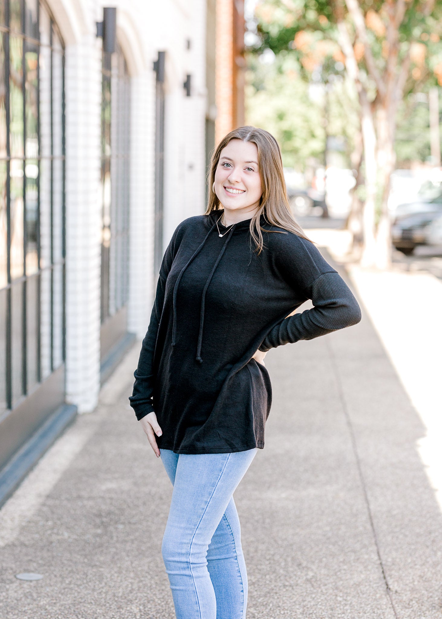 Brunette model wearing black hoodie with tie in hood.