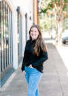 Brunette model wearing black hoodie with jeans.