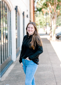 Brunette model wearing black hoodie with jeans.