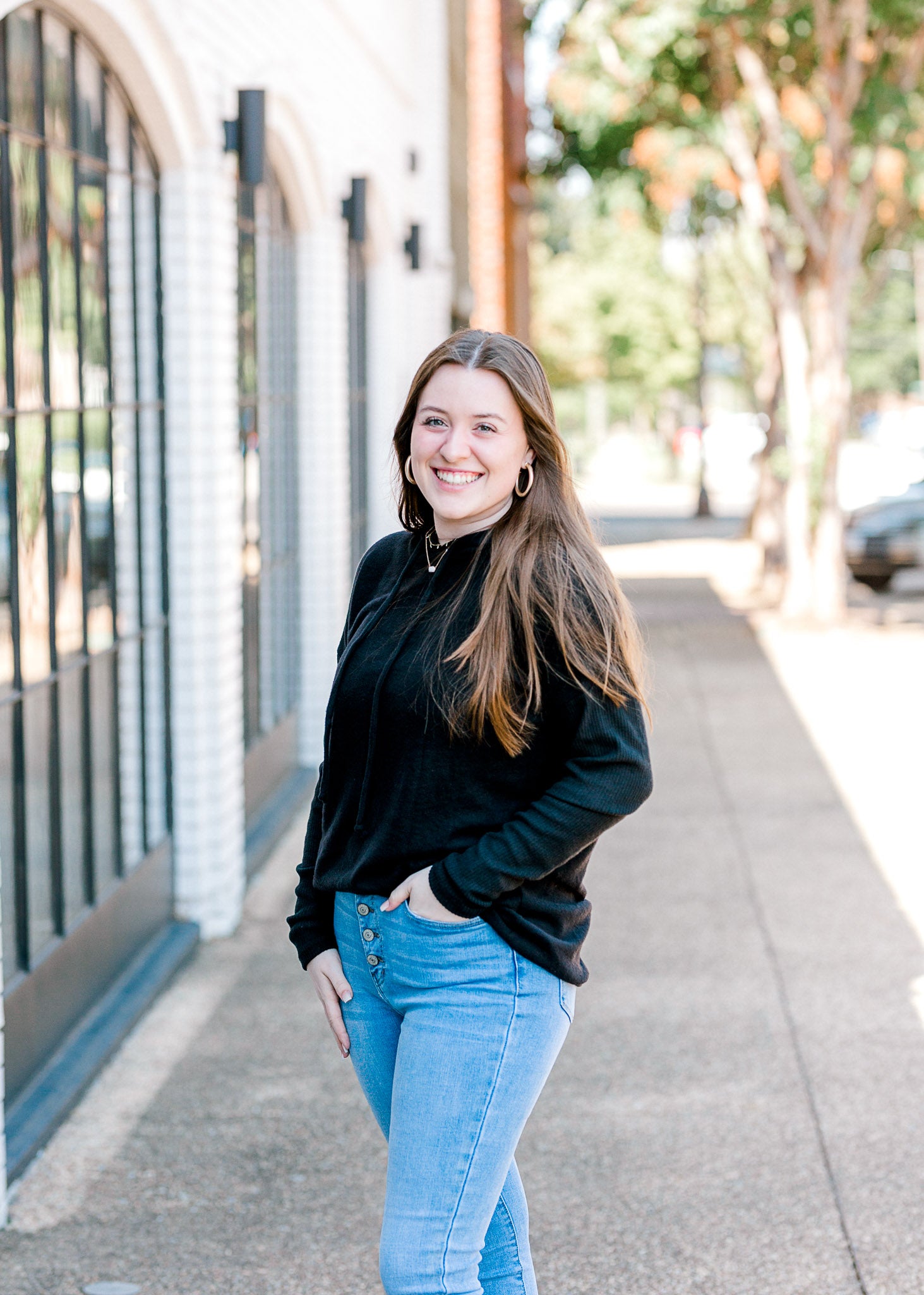 Brunette model wearing black hoodie with jeans.
