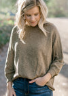 Blonde model wearing olive sweater. 